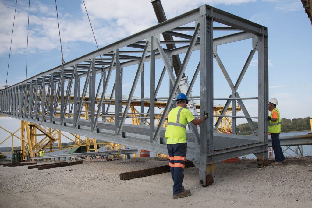 Workers lifting steel with crane